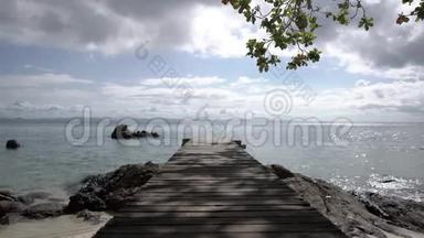 复古和古老的木桥在海滩和海洋的中午与海滩，海洋，阳光，岩石，风和波浪周围。